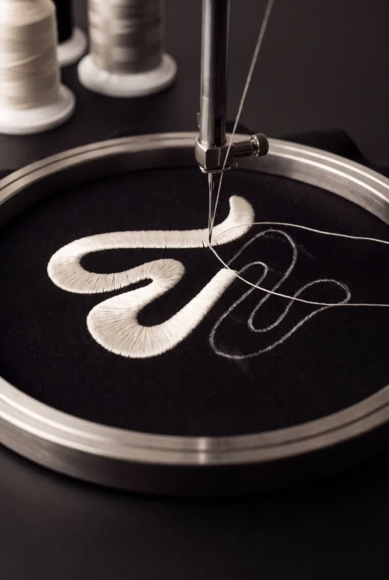 Embroidery machine stitching the BLNKK logo
